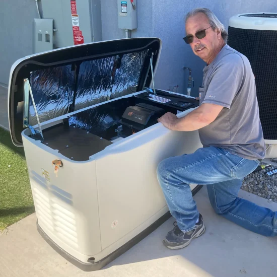 Bruce Goodkin Electric A man kneels beside an open standby generator outdoors, inspecting its control panel next to an air conditioning unit.